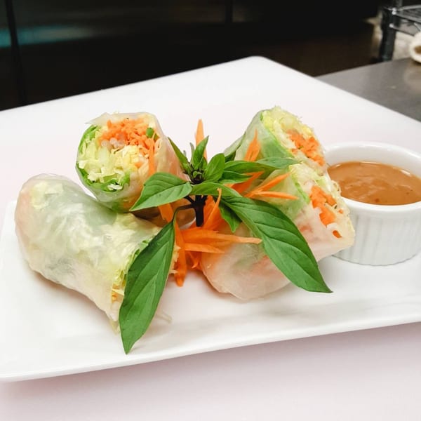 Fresh Thai spring rolls with shredded vegetables and basil, served with peanut sauce.