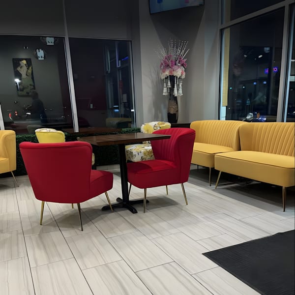 Interior of Thai House Bistro with red chairs, yellow banquettes, and a dark table by large windows.