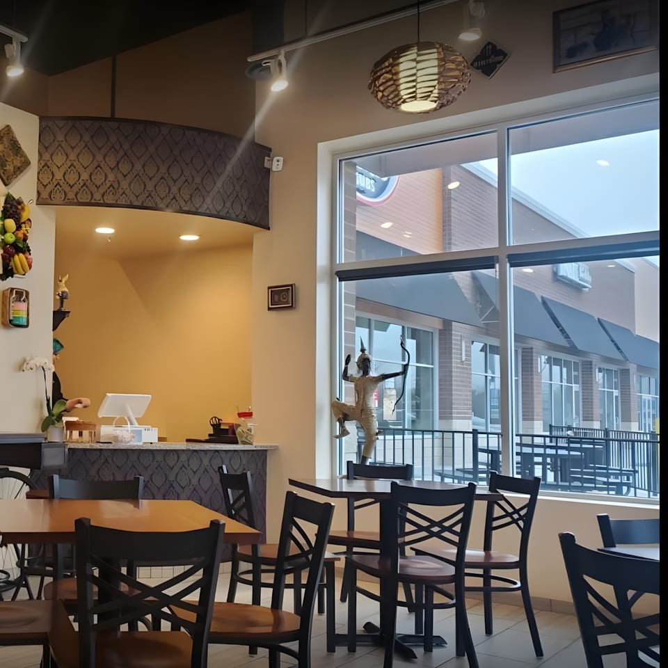 Interior of Thai House Bistro with dining tables, a counter, and a large window overlooking an outdoor area.